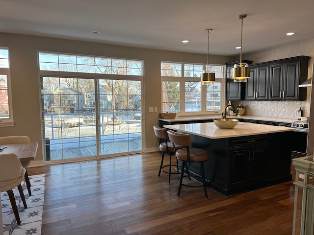 kitchen featuring a center island, light countertops, visible vents, wood finished floors, and dark cabinets