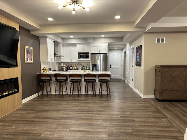 kitchen featuring visible vents, white cabinets, dark wood-style floors, appliances with stainless steel finishes, and a peninsula