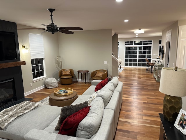 living area featuring recessed lighting, a large fireplace, ceiling fan, wood finished floors, and baseboards