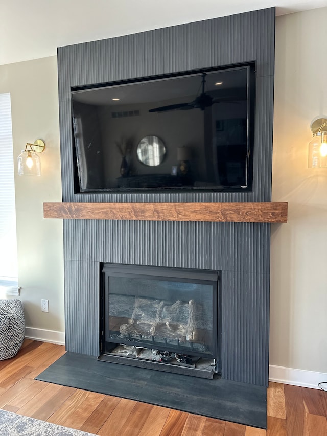 room details with a fireplace with flush hearth, wood finished floors, visible vents, and baseboards