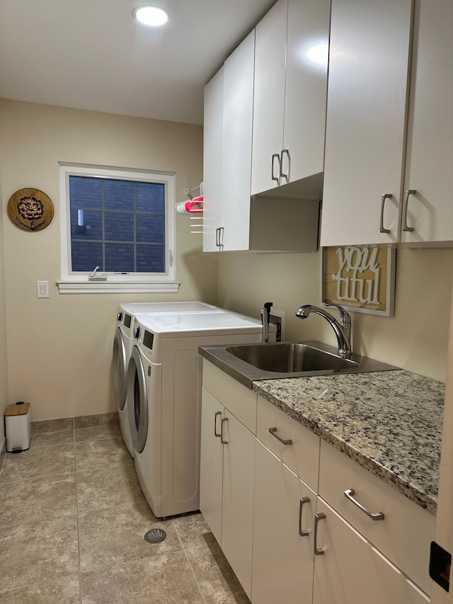 washroom featuring separate washer and dryer, a sink, cabinet space, and baseboards