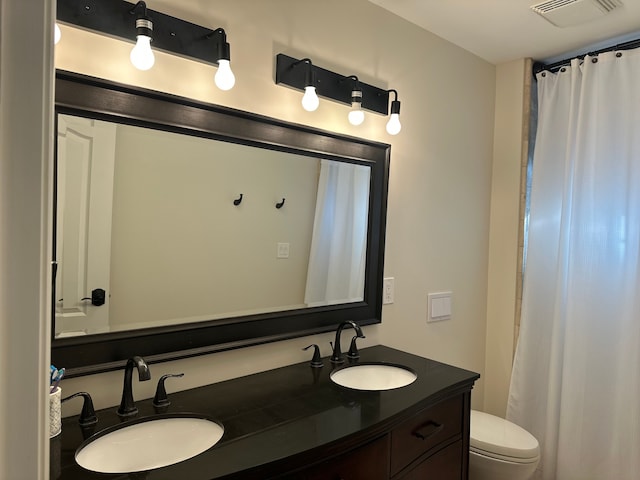 bathroom with toilet, double vanity, a sink, and visible vents