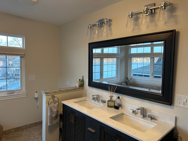 full bath with tile patterned flooring, a sink, baseboards, and double vanity