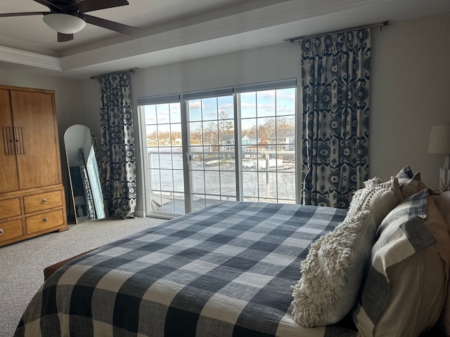 carpeted bedroom with arched walkways, a raised ceiling, a ceiling fan, and access to exterior