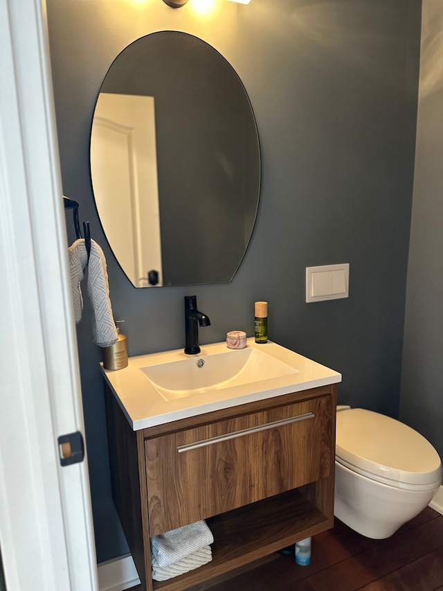 half bathroom featuring toilet, wood finished floors, and vanity