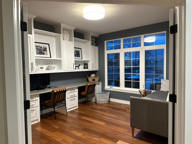 office featuring dark wood-style floors, baseboards, visible vents, and built in study area