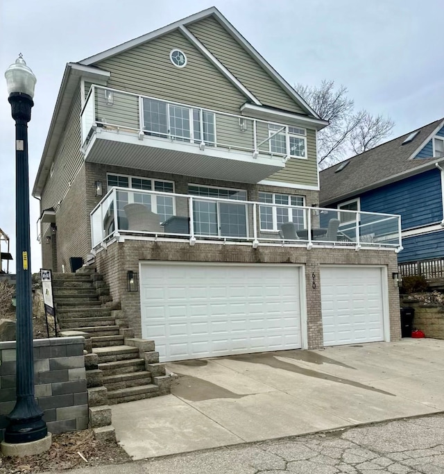 view of front of home with a balcony, a garage, brick siding, stairs, and concrete driveway