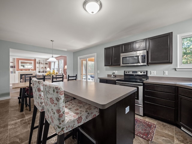 kitchen with a center island, decorative light fixtures, stainless steel appliances, light countertops, and a kitchen breakfast bar