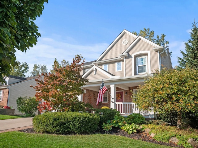 view of front of property with driveway, covered porch, a garage, and brick siding