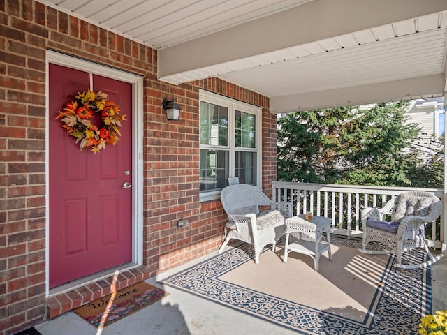 entrance to property with a porch and brick siding