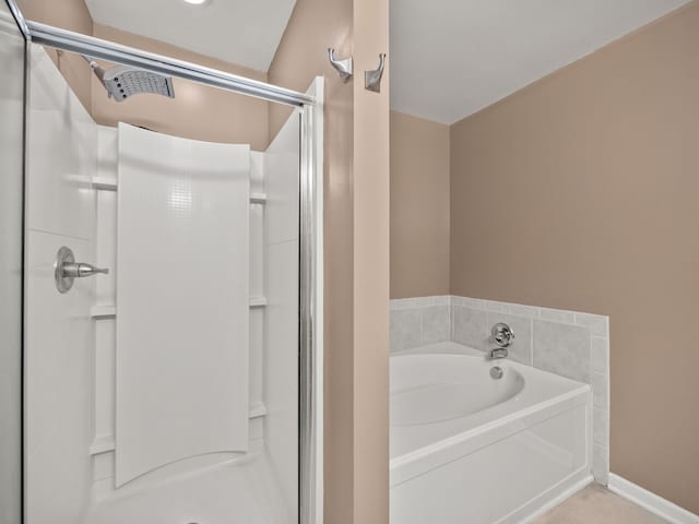 bathroom with a stall shower, baseboards, and a garden tub