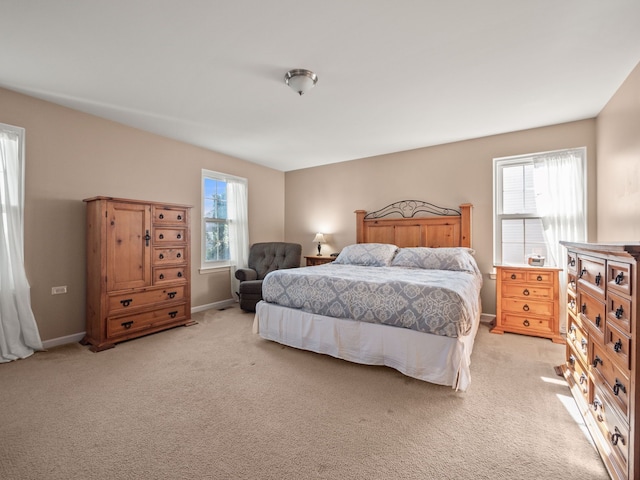 bedroom featuring light carpet, multiple windows, and baseboards