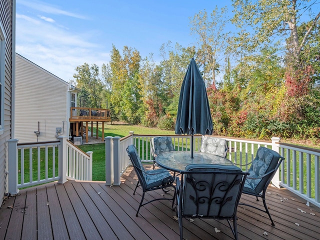 deck with outdoor dining area and a lawn