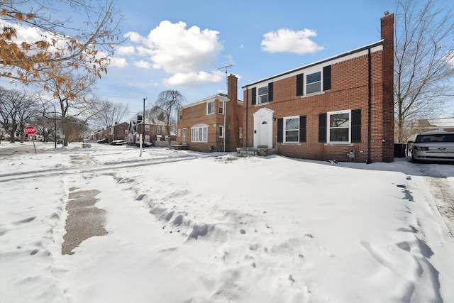 view of front of property featuring a chimney and brick siding