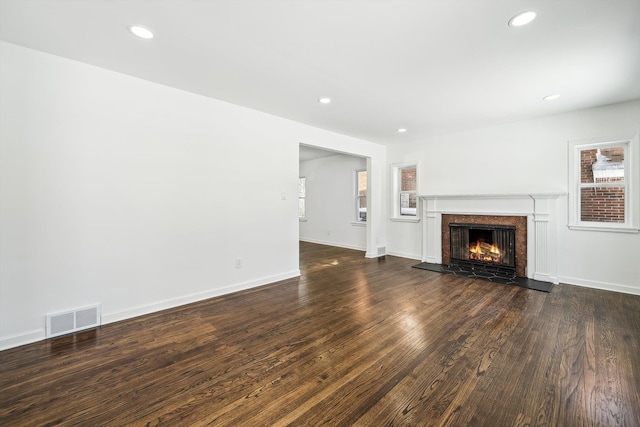 unfurnished living room with baseboards, visible vents, a tile fireplace, wood finished floors, and recessed lighting