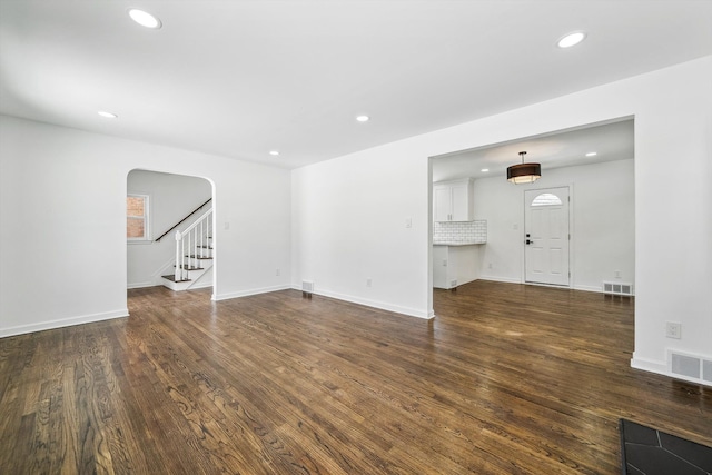 unfurnished living room featuring recessed lighting, wood finished floors, visible vents, and stairs