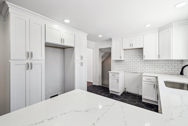 kitchen featuring tasteful backsplash, recessed lighting, white cabinets, a sink, and dark tile patterned flooring