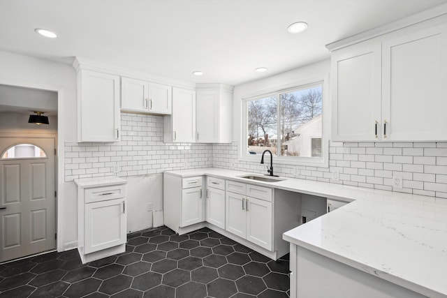 kitchen with white cabinets, light stone counters, a sink, backsplash, and recessed lighting