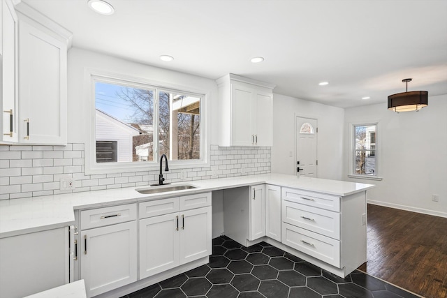 kitchen with a peninsula, tasteful backsplash, white cabinets, and a sink