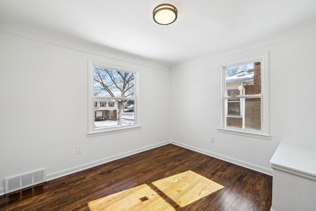 empty room featuring baseboards, visible vents, a wealth of natural light, and wood finished floors