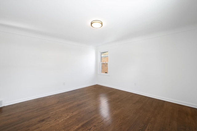 spare room with dark wood-style floors and baseboards