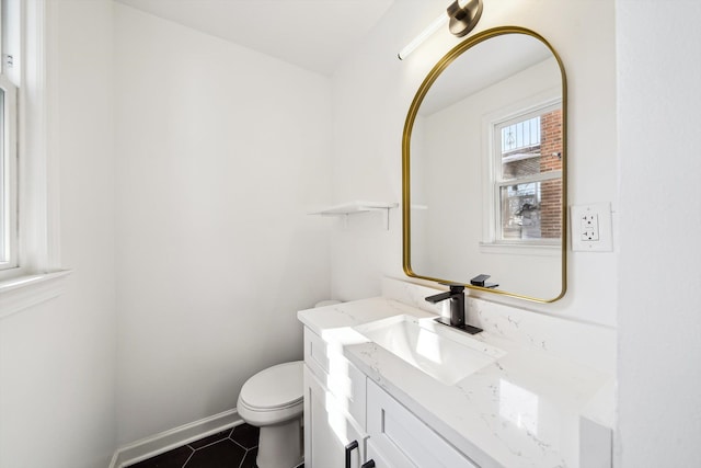 half bathroom with toilet, tile patterned flooring, baseboards, and vanity