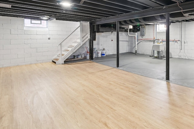 below grade area featuring stairs, a sink, wood finished floors, and electric panel