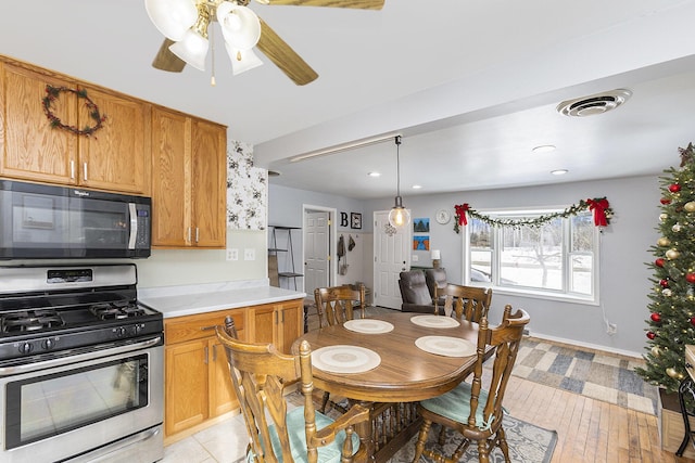 kitchen with visible vents, baseboards, stainless steel gas range, light countertops, and black microwave