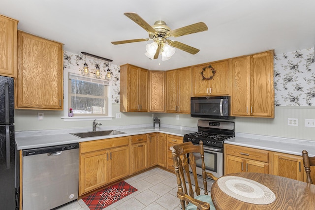 kitchen featuring stainless steel appliances, a sink, light countertops, and wallpapered walls