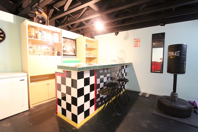 bar featuring a dry bar, concrete floors, and refrigerator