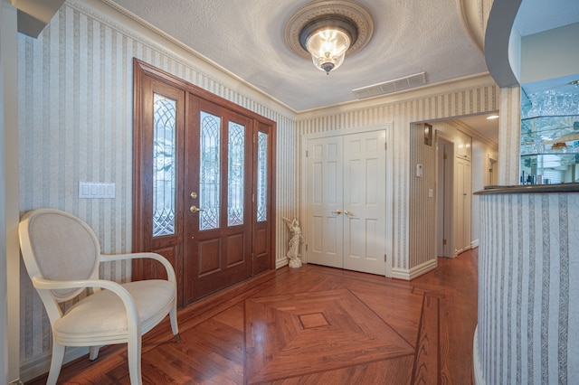 foyer entrance with visible vents, a textured ceiling, baseboards, and wallpapered walls