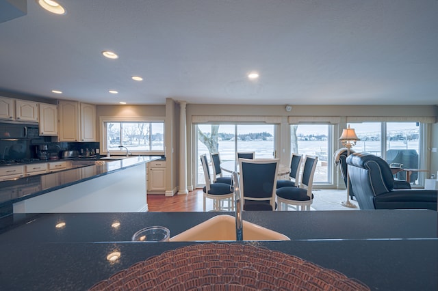 kitchen with dark countertops, light wood-type flooring, black microwave, a sink, and recessed lighting