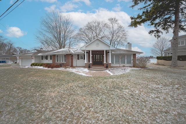 view of front of property with a porch, a chimney, an attached garage, and brick siding
