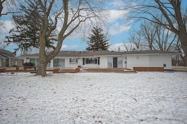 snow covered house with a chimney and a wooden deck