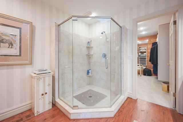 bathroom featuring a stall shower, wood finished floors, and wallpapered walls