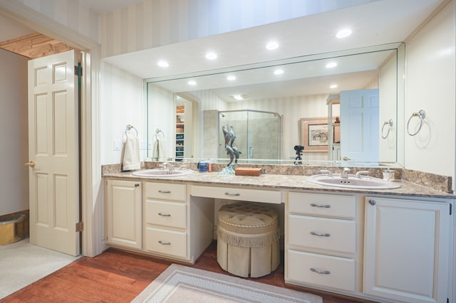 full bathroom featuring double vanity, wood finished floors, a stall shower, and a sink