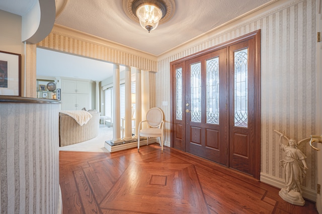 foyer entrance featuring baseboards, a textured ceiling, and wallpapered walls