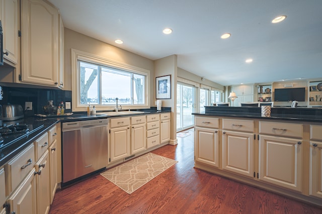 kitchen with dark wood-type flooring, cream cabinets, a sink, and stainless steel dishwasher