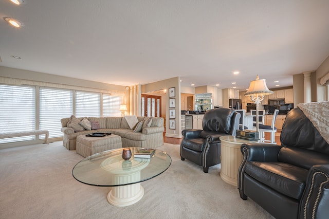 living area featuring ornate columns, recessed lighting, and light colored carpet