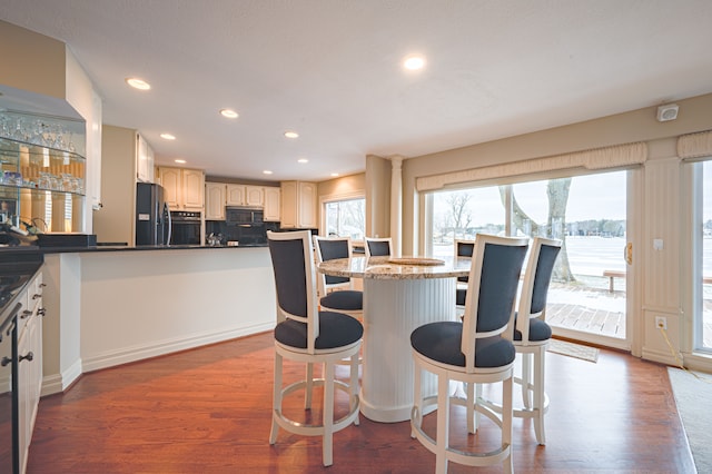 kitchen with a breakfast bar, stainless steel fridge, backsplash, and wood finished floors