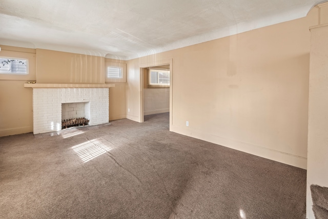 unfurnished living room featuring a healthy amount of sunlight, a brick fireplace, and carpet floors