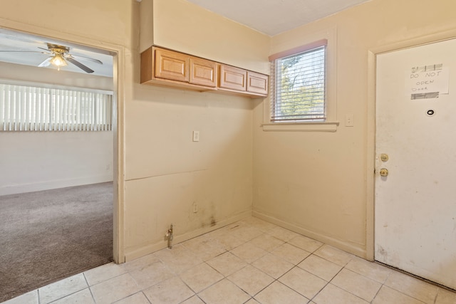 laundry area with light tile patterned floors, a ceiling fan, light colored carpet, and baseboards