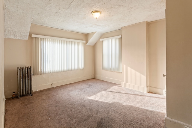 carpeted spare room with radiator and a textured ceiling