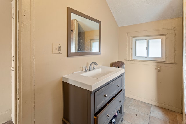 bathroom with tile patterned floors, a textured ceiling, baseboards, vanity, and vaulted ceiling