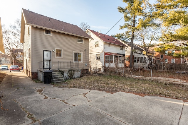 rear view of property featuring concrete driveway and fence