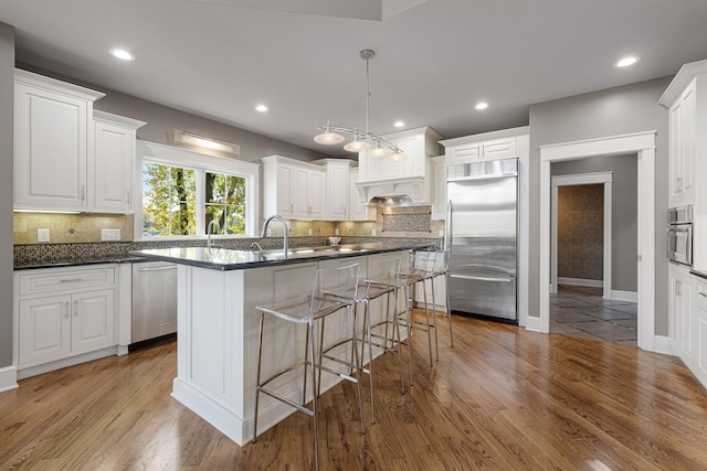 565 Golden Bear Ct, Saint Joseph, MI 49085 - kitchen featuring dark countertops, a kitchen island with sink, stainless steel appliances, and wood finished floors