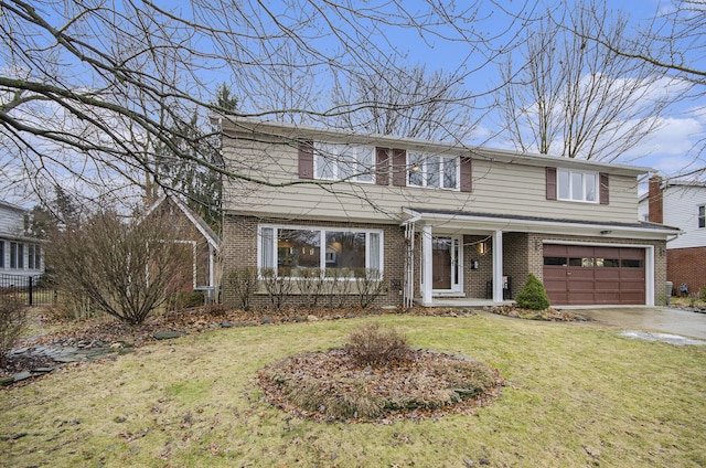 traditional home with a garage, a front yard, brick siding, and driveway