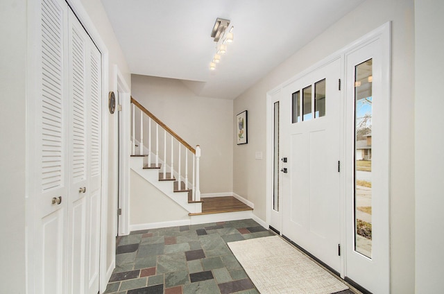 foyer featuring stairway and baseboards