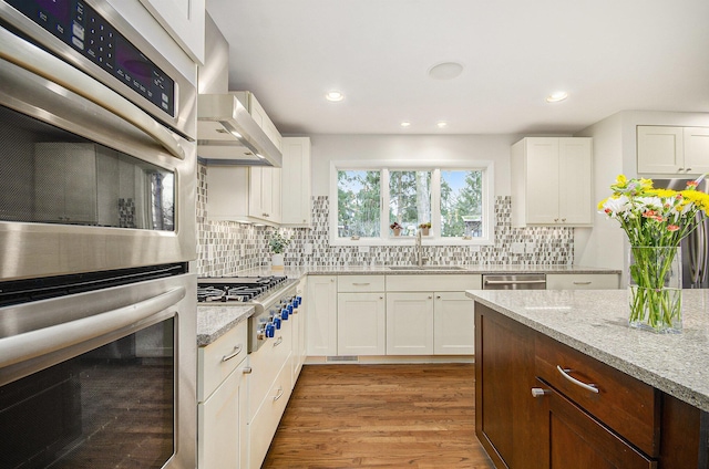 kitchen with appliances with stainless steel finishes, backsplash, a sink, and light stone counters