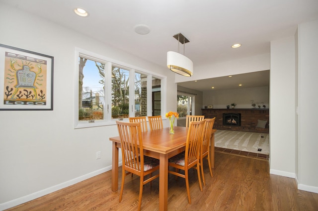 dining space featuring recessed lighting, a fireplace, baseboards, and wood finished floors